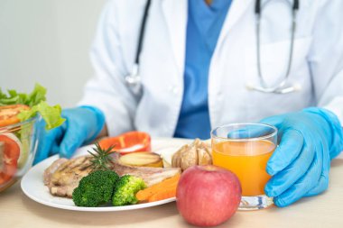 Beslenme uzmanı doktor hasta için çeşitli sağlıklı sebzeler tutuyor..