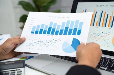 Modern ofis, finans ve iş konseptinde grafik grafik grafiği ve hesap makinesiyle çalışan ve finansal raporları analiz eden Asyalı muhasebeci.