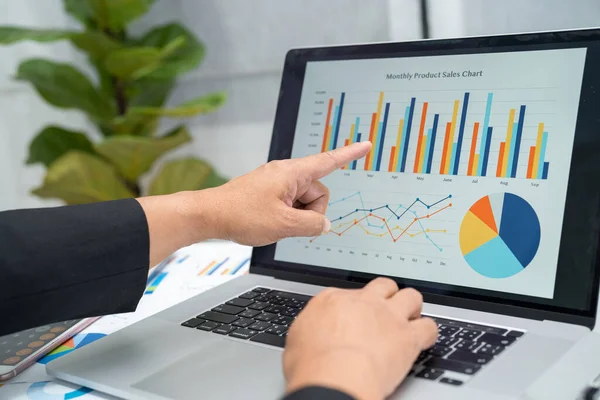 Modern ofis, finans ve iş konseptinde grafik grafik grafiği ve hesap makinesiyle çalışan ve finansal raporları analiz eden Asyalı muhasebeci.