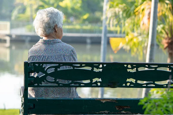 亚洲老年妇女沮丧而忧郁地坐在秋日公园的长椅上 — 图库照片
