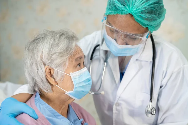 Doktor, enfeksiyonu Covid-19 Coronavirus 'u korumak için hastanede yüz maskesi takan yaşlı ve yaşlı bir kadını kontrol ediyor..