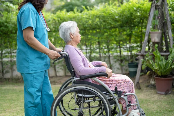 介護士のヘルプとケアアジアの高齢女性高齢者の女性患者介護病院の駐車場で車椅子に座って 健康的な強い医療の概念 — ストック写真