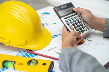 Mimari ev planı projesine sahip Asyalı mühendis şema, grafik ve sarı miğfer ve mühendislik inşaat araçları.