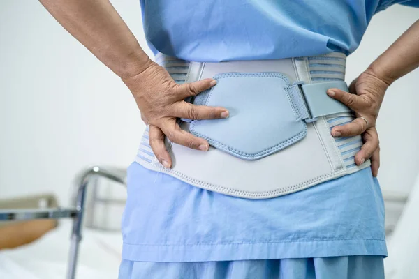 Asian lady patient wearing back pain support belt for orthopedic lumbar with walker.