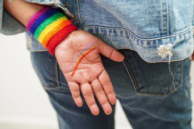 Gökkuşağı bileklik takan Asyalı kadın, beyaz arka planda kırpma yolu ile izole edildi, LGBT gurur ayının sembolü, Haziran sosyal ortamında gey, lezbiyen, biseksüel, transseksüel, insan hakları kutlamaları.
