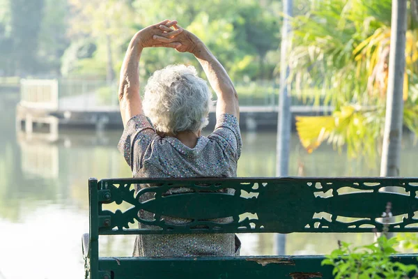 亚洲老妇人快乐而又新鲜地坐在秋日公园的长椅上 — 图库照片