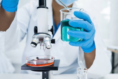 Laboratuvarda mikroskopla çalışan Asyalı biyokimyacı ya da mikrobiyolog. Coronavirus salgınını korumak için. Covid19, bakteri ve mikroplar..