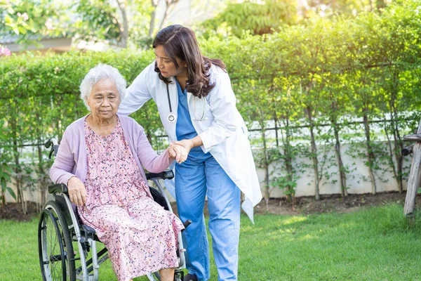 Doctor help and care Asian senior or elderly old lady woman patient sitting on wheelchair at park in nursing hospital ward, healthy strong medical concept.