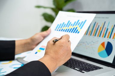 Modern ofis, finans ve iş konsepti grafikleriyle muhasebe projesini inceleyen Asyalı muhasebeci.