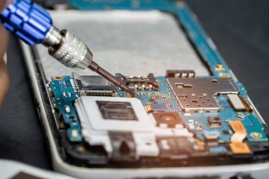 Teknisyen, cep telefonunun içinde lehim kullanarak tamir ediyor. Bütünleşik devre. veri kavramı, donanım, teknoloji.