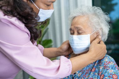 Bakıcı, Asyalı yaşlı ya da yaşlı kadın tekerlekli sandalyede oturan ve güvenlik enfeksiyonunu korumak için maske takan Covid 19 Coronavirus 'a yardım ediyor..