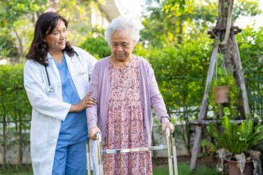 Asya 'lı yaşlı ve yaşlı kadınlara yardım ve yataklık etmek için parkta yürürken sağlıklı bir şekilde yürüyen yaşlı kadın kullanılıyor..