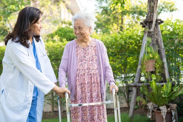 Help and care Asian senior or elderly old lady woman use walker with strong health while walking at park in happy fresh holiday.