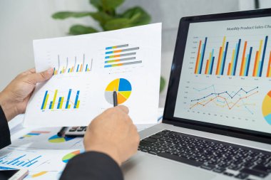 Modern ofis, finans ve iş konseptinde grafik grafik grafiği ve hesap makinesiyle çalışan ve finansal raporları analiz eden Asyalı muhasebeci.