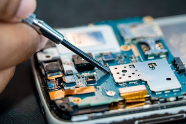 Teknisyen, cep telefonunun içinde lehim kullanarak tamir ediyor. Bütünleşik devre. veri kavramı, donanım, teknoloji.