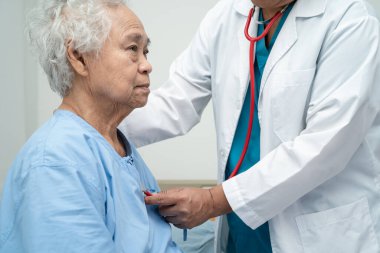 Steteskoplu bir doktor yaşlı ya da yaşlı kadın hastayı kontrol ediyor. Hemşirelik hastanesi koğuşunda bir yatakta oturuyor. Sağlıklı, güçlü bir tıbbi konsept..