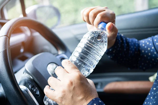 Asian woman driver holding bottle for drink water while driving a car. Plastic hot water bottle cause fire.