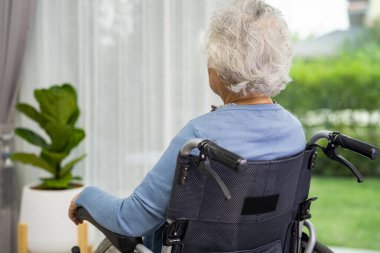 Tekerlekli sandalyede oturan yaşlı bir kadın birini beklerken pencereden dışarı bakıyor. Üzücü, melankolik ve depresif.