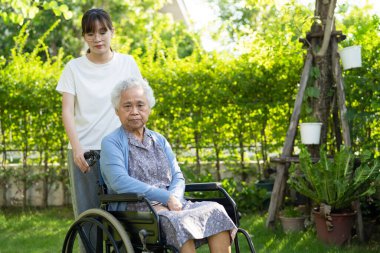 Bakıcı yardım ve bakım Asyalı yaşlı ya da yaşlı kadın hasta parkta tekerlekli sandalyede oturuyor, sağlıklı güçlü tıbbi konsept.