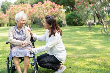 Bakıcı yardım ve bakım Asyalı yaşlı ya da yaşlı kadın hasta parkta tekerlekli sandalyede oturuyor ve mutlu, sağlıklı güçlü tıbbi konsept..