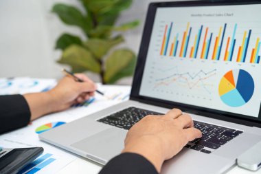 Modern ofis, finans ve iş konseptinde grafik grafik grafiği ve hesap makinesiyle çalışan ve finansal raporları analiz eden Asyalı muhasebeci.