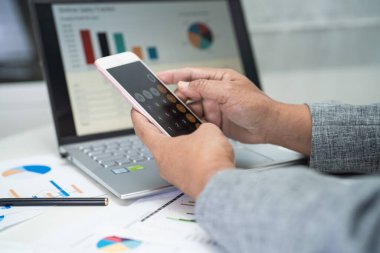 Modern ofis, finans ve iş konsepti grafikleriyle muhasebe projesini inceleyen Asyalı muhasebeci.