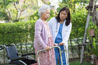 Asya 'lı yaşlı ve yaşlı kadınlara yardım ve yataklık etmek için parkta yürürken sağlıklı bir şekilde yürüyen yaşlı kadın kullanılıyor..