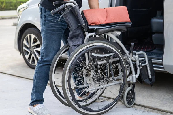 Asian woman folding and lift up wheelchair into her car. Accessibility concept.