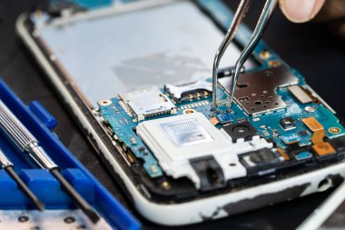 Teknisyen, cep telefonunun içinde lehim kullanarak tamir ediyor. Bütünleşik devre. veri kavramı, donanım, teknoloji.