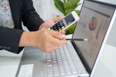 Modern ofis, finans ve iş konseptinde grafik grafik grafiği ve hesap makinesiyle çalışan ve finansal raporları analiz eden Asyalı muhasebeci.