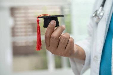 Asyalı doktor eğitimi, hastane koğuşunda mezuniyet şapkasıyla, zeki dahi tıp konseptiyle öğreniyor..