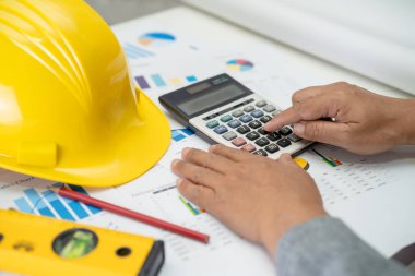 Mimari ev planı projesine sahip Asyalı mühendis şema, grafik ve sarı miğfer ve mühendislik inşaat araçları.