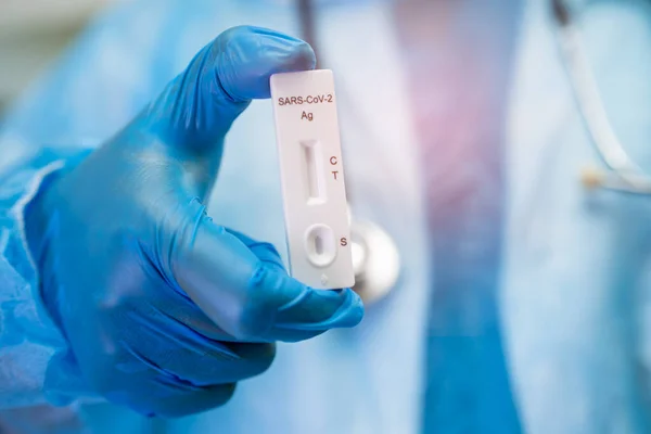 Asian doctor in PPE suit holding Saliva Antigen Test Kit for check Covid19 coronavirus in hospital.