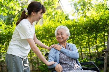 Bakıcı yardım ve bakım Asyalı yaşlı ya da yaşlı kadın hasta parkta tekerlekli sandalyede oturuyor, sağlıklı güçlü tıbbi konsept.