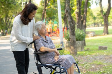 Bakıcı yardım ve bakım Asyalı yaşlı ya da yaşlı kadın hasta parkta tekerlekli sandalyede oturuyor ve mutlu, sağlıklı güçlü tıbbi konsept..