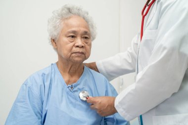 Steteskoplu bir doktor yaşlı ya da yaşlı kadın hastayı kontrol ediyor. Hemşirelik hastanesi koğuşunda bir yatakta oturuyor. Sağlıklı, güçlü bir tıbbi konsept..