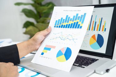 Modern ofis, finans ve iş konsepti grafikleriyle muhasebe projesini inceleyen Asyalı muhasebeci.