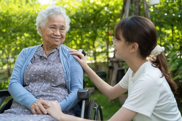 Caregiver help and care Asian senior or elderly old lady woman patient sitting on wheelchair in park, healthy strong medical concept.