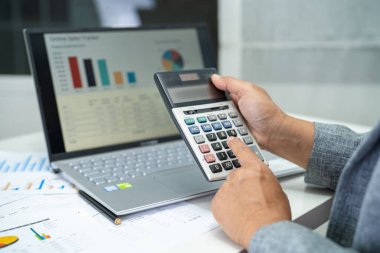 Modern ofis, finans ve iş konsepti grafikleriyle muhasebe projesini inceleyen Asyalı muhasebeci.