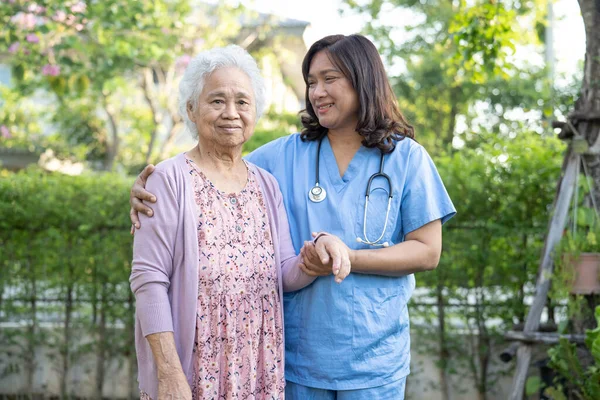 Doctor help and care Asian senior or elderly old lady woman use walker with strong health while walking at park in happy fresh holiday.