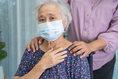 Bakıcı, Asyalı yaşlı ya da yaşlı kadın tekerlekli sandalyede oturan ve güvenlik enfeksiyonunu korumak için maske takan Covid19 Coronavirus 'a yardım ediyor..