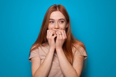 Modaya uygun bir kadının mavi arka planında portresi. İzole edilmiş beyaz. Genç ve güzel bir kadın. El hareketi. Çilli kızıl kadın dilek işareti yapıyor..