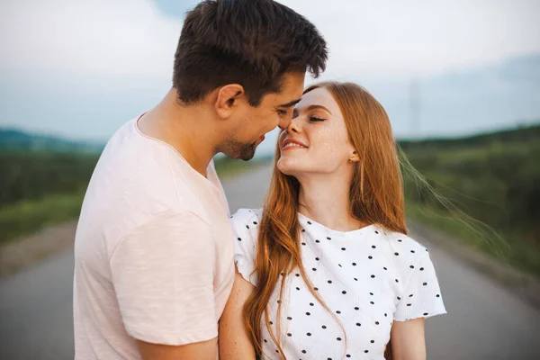 Modeporträt eines Paares, das sich im Sonnenlicht küsst. Frühlingszeit. Schöne Liebhaberin, die sich auf einer Straße umarmt. — Stockfoto