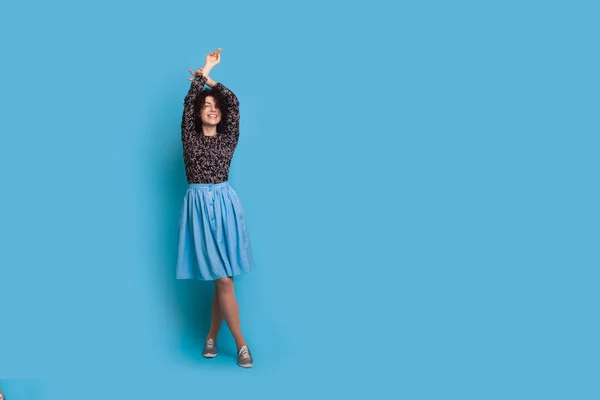 Mujer rizada en los anuncios de vestido sobre fondo azul. Cabello rizado. Un gesto de mano. Persona de moda. Elegante atuendo de concepto. — Foto de Stock