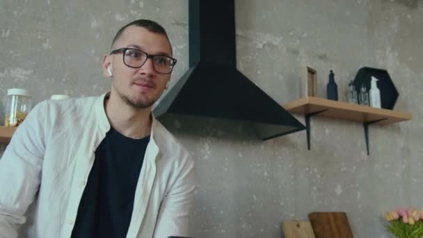 O vídeo com um menino que entrou na cozinha para comer uma maçã durante esse tempo chamando um colega ao telefone, sentado na mesa, começou a se comunicar. Moderno — Vídeo de Stock