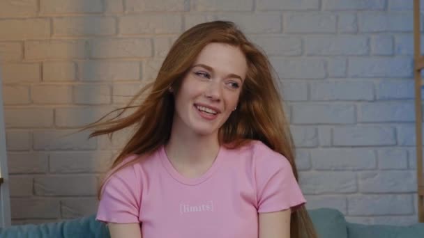 Video. Portrait of a red-haired Caucasian woman with freckled face talking about her to the camera. Brick wall. Cheerful communication — Stock Video