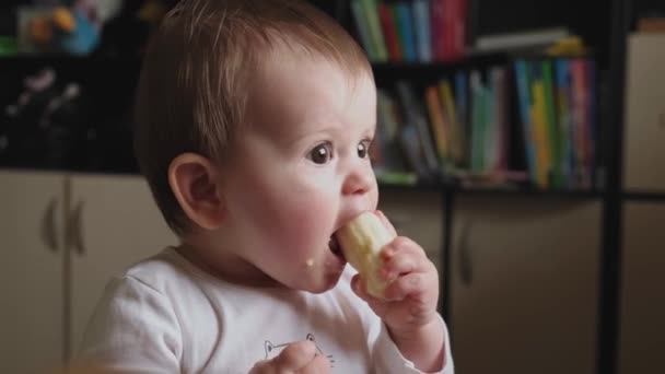 赤ちゃんがバナナを手に持って小さな口で噛んだビデオ。拍手を。面白い幸せな赤ちゃん。赤ちゃん。健康的な子供時代. — ストック動画