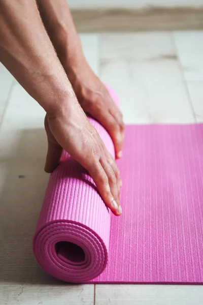 Imagen de cerca de las manos de un hombre desenrollando la esterilla deportiva preparándose para hacer un entrenamiento productivo. Hombre manos alfombra rodante, gran diseño para cualquier propósito. Deporte — Foto de Stock