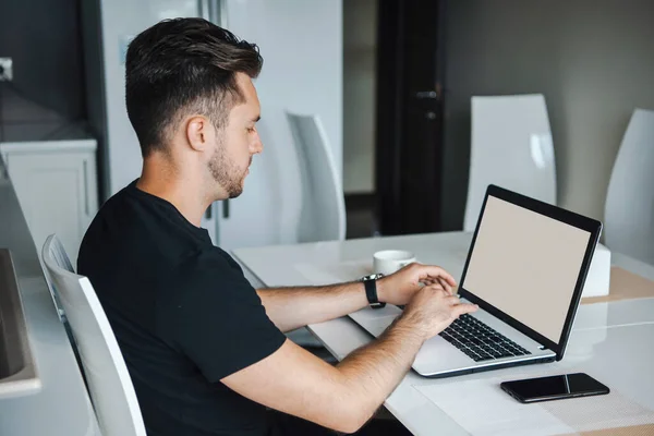 Sidovy av en man som sitter vid skrivbordet och skriver på en dator. Affärsman som använder laptop. En upptagen affärsman. Kontorsarbetare. — Stockfoto