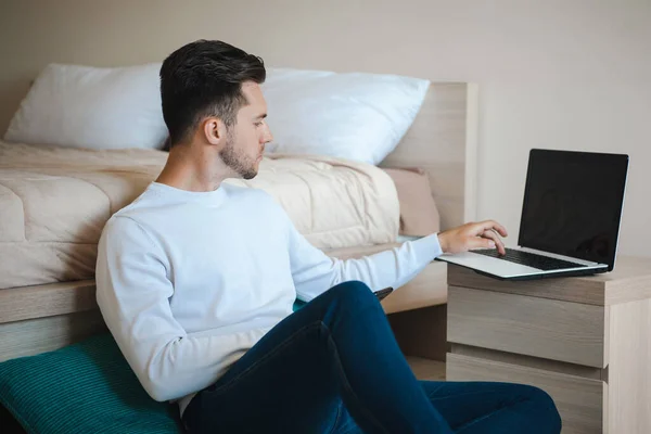 Hombre sentado en el suelo apoyado en la cama y escribiendo en el ordenador. Carrera en línea. Tecnología de Internet. Hombre sentado. Tecnología informática. Negocio —  Fotos de Stock